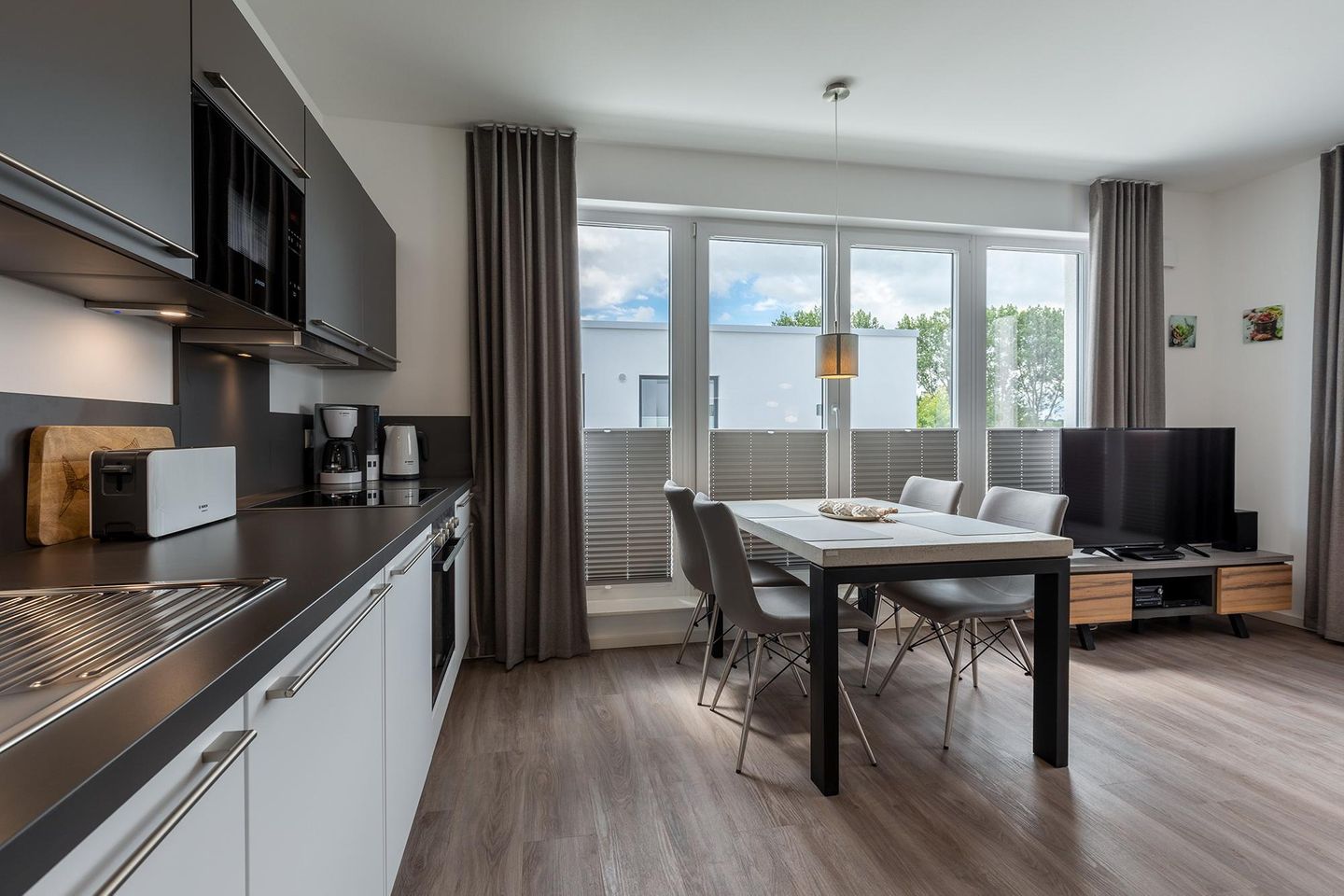 Aparthotel Ostseeallee Aparthotel Ostseeallee 2-17 Boltenhagen - Wohn-/Essbereich mit Küchenzeile, Esstisch und Sitzgelegenheiten