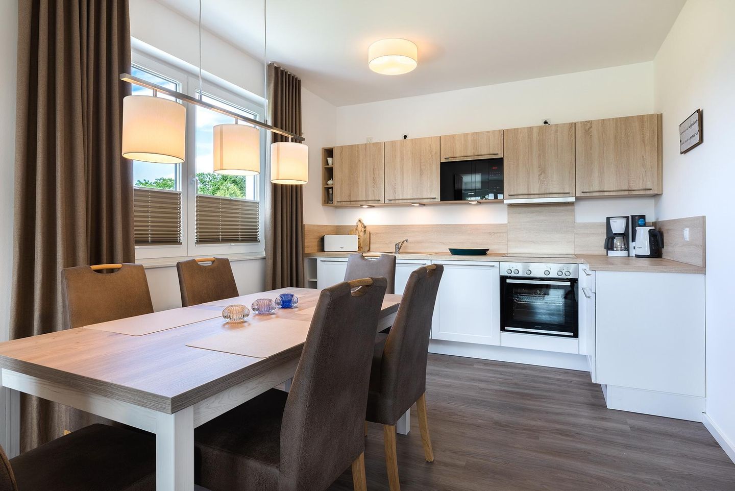 Aparthotel Ostseeallee Aparthotel Ostseeallee 3-28 Boltenhagen - Wohn-/Essbereich mit Tisch, Sitzgelegenheiten und Küchenzeile