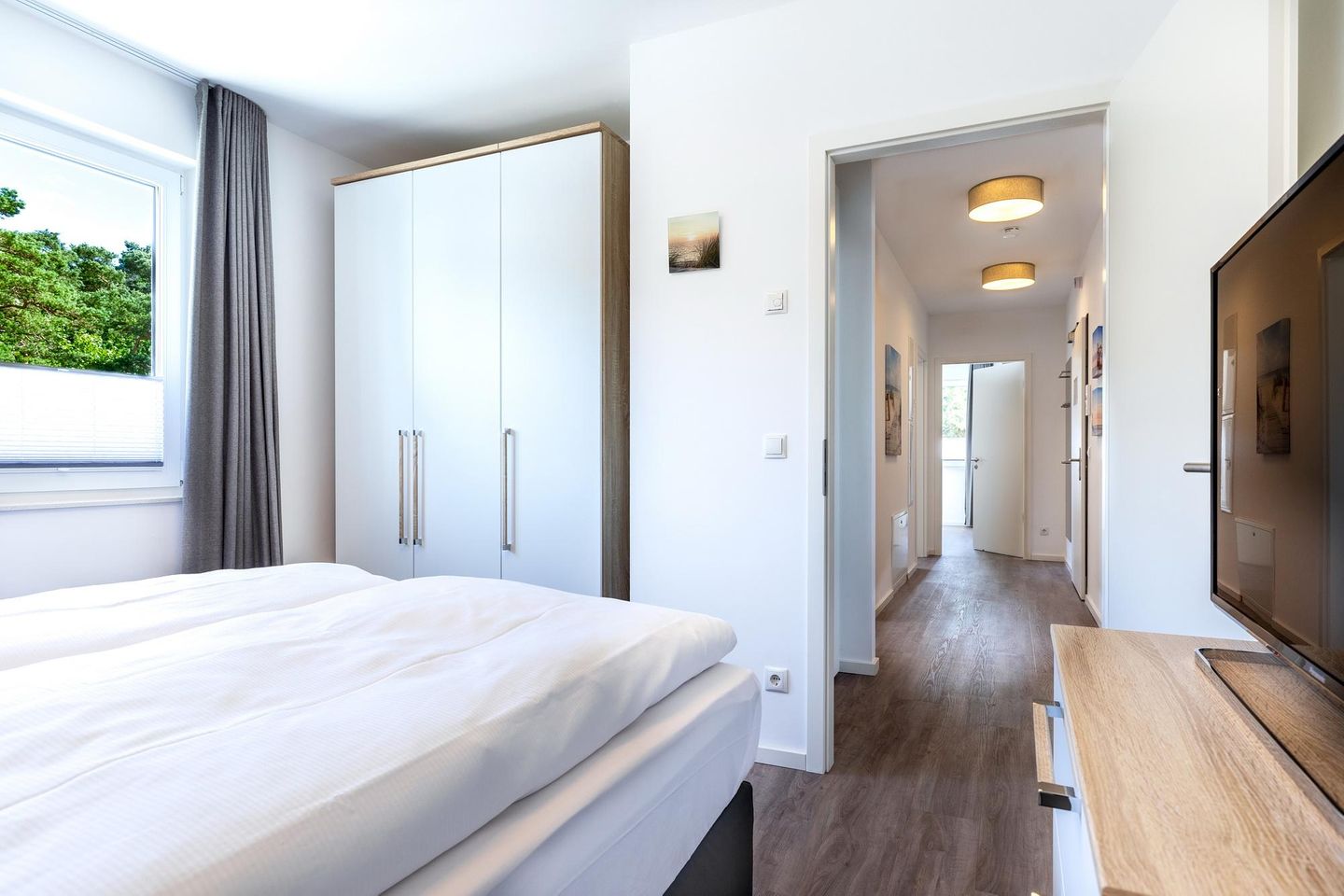 Aparthotel Ostseeallee Aparthotel Ostseeallee 5-47 Boltenhagen - Schlafzimmer "1" mit Boxspringbett, TV und Blick zum Flur