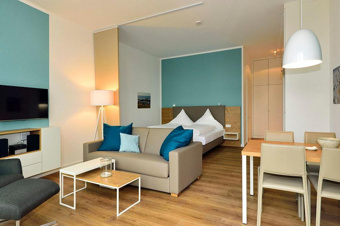 Aparthotel Anna Düne Aparthotel Anna Düne 0-04 Wangerooge - Wohn/ Essbereich mit Couch, Fernseher und Esstisch