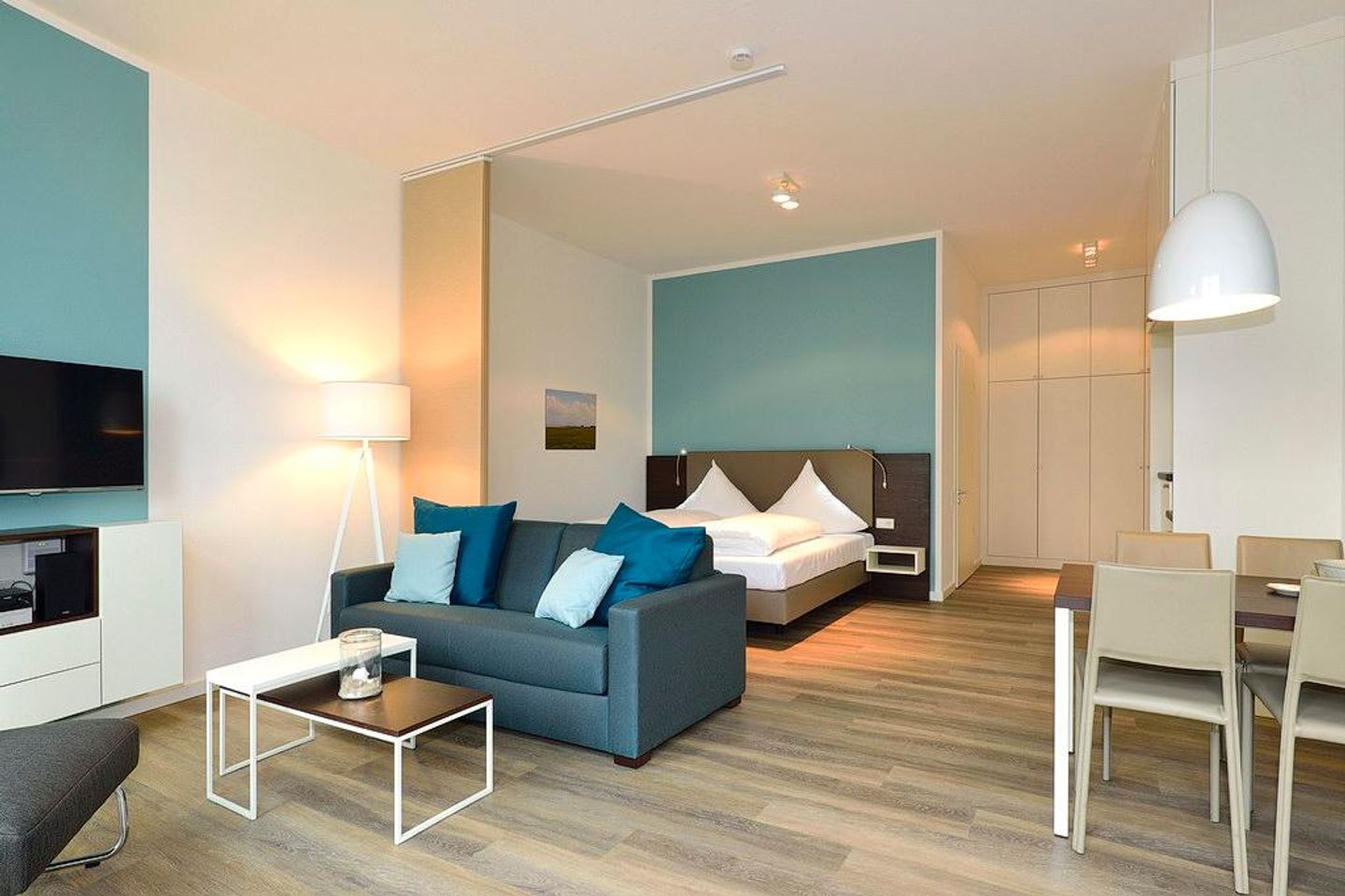 Aparthotel Anna Düne Aparthotel Anna Düne 0-07 Wangerooge - Wohn/ Essbereich mit Couch, Fernseher und Esstisch