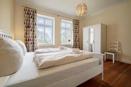 Schlafzimmer zur Gartenseite mit großem Doppelbett und Kleiderschrank Ferienwohnung Gut Hardesby