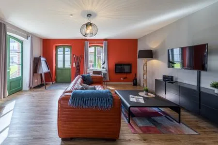 Ferienwohnung Müritzperle Klink - Blick ins Wohnzimmer mit roter Couch  Müritzperle