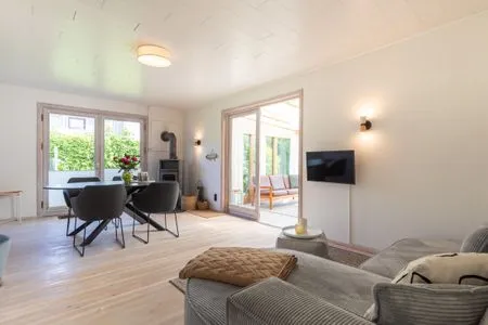 Wohnzimmer mit TV-Ecke, Esstisch und Ofen VITA Sonnholm