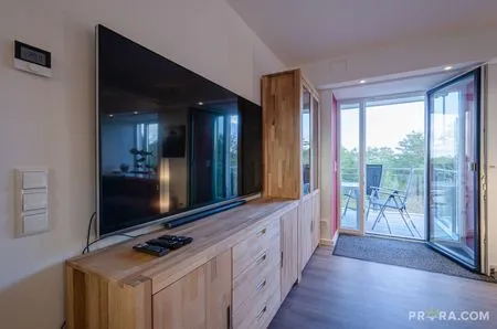 Wohn/Essbereich: Couch und Sessel, TV, Zugang zum Balkon FeWo Strandidyll in PRORA - 9.31