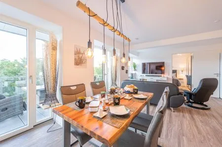 Wohn/Essbereich: Sofa, Sitzbereich, Essbereich, TV, Elektrokamin, Zugang zum Balkon FeWo Meerlust in PRORA - 4.42