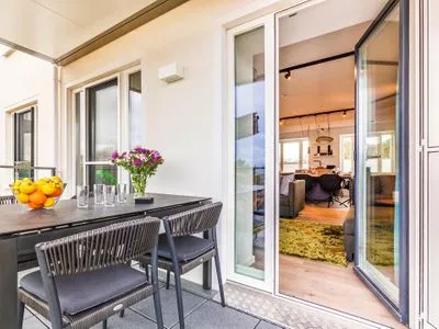 Wohn-/Essbereich: Couchgruppe mit Tisch, Smart-TV, Essbereich, Zugang zum Balkon mit Tisch und Stühlen (Seeseite), Sonne FeWo Hideaway in PRORA - 2.45