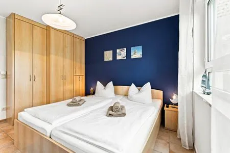 Schlafzimmer mit Doppelbett, Kleiderschrank und TV Residenz am Strand Wohnung 4-58