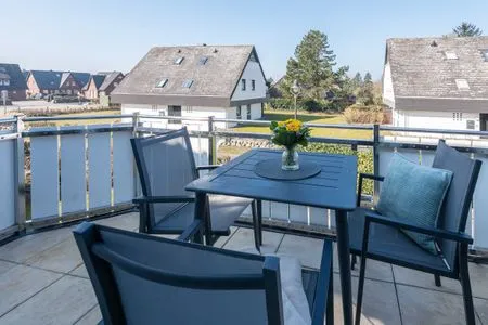 auf dem Westbalkon von Ferienwohnung Carmen App. 12 stehen drei Stühle und ein Tisch mit Blumen Haus Carmen App. 12