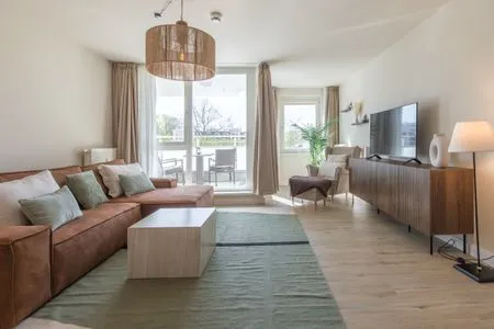 Ferienwohnung Küstenglück in Zingst helles Wohnzimmer mit Couch, TV und Zugang zum Balkon  Küstenglück