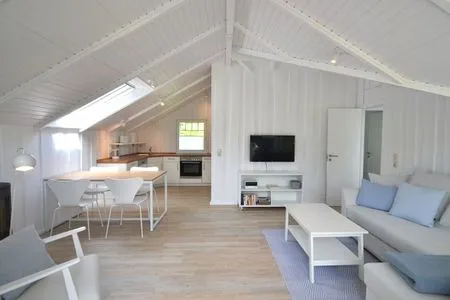 Wohnzimmer mit TV, Ofen und offener Küche Lille Hus