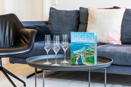 Wohn/Essbereich: Sofa, Sessel, TV, Zugang zum Balkon FeWo MariSol in PRORA Strandnah mit Meerblick & Sauna - 5.22