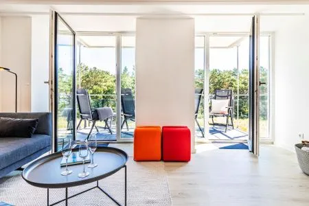 Wohn/Essbereich: Sofa, Sessel, TV, Zugang zum Balkon FeWo MariSol in PRORA Strandnah mit Meerblick & Sauna - 5.22