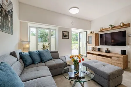 Wohnzimmer: Schlafsofa und Sessel, TV, Essbereich, Zugang zur Terrasse FeWo Proras Strandhaus in PRORA - 9.03