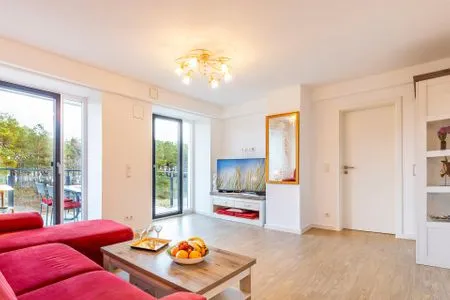 Wohnzimmer: Couch, TV, Essbereich, Zugang zum Balkon FeWo Seeigel in PRORA - 6.34