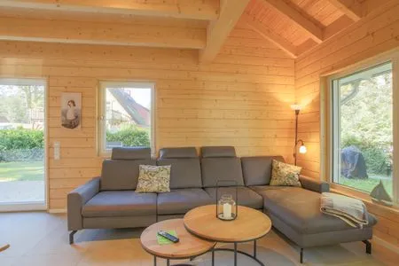 Einfamilienhaus Am Hafen 21 in Zieslow — gemütliches Wohnzimmer mit Holzvertäfelung, Ecksofa und Blick in den Garten  Am Hafen 21