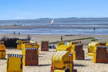 Strandkörbe am sonnigen Sandstrand von Cuxhaven-Duhnen, im Hintergrund das Wattenmeer und die Insel Neuwerk. Haus Pacific Duhnen Nr. 91