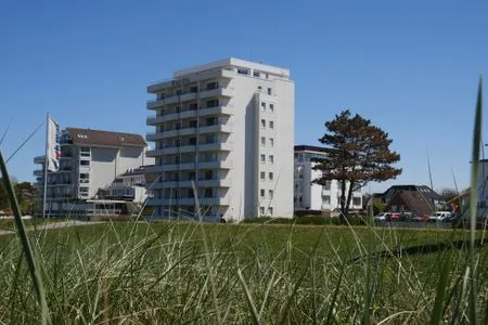 Hohe Gräser vor dem Gebäude Pacific Duhnen, das eine exponierte Lage am Strand von Cuxhaven mit Meerblick hat. Haus Pacific Duhnen Nr. 91