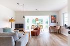  Boddenblick 1 Born auf dem Darß - Wohnzimmer mit Sofa, rotem Sessel, TV, Essbereich am Fenster und Schreibtisch.
