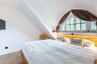  Boddenblick 1 Born auf dem Darß - Schlafzimmer mit Doppelbett, Holz-Kopfteil, Kissen ‚Meer verliebt‘ und Fenster.