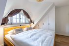  Boddenblick 1 Born auf dem Darß - Schlafzimmer mit Doppelbett, Holz-Kopfteil, Einbauschränken und Fensterfront.