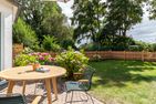  Boddenblick 1 Born auf dem Darß - Terrasse mit Holztisch und Stühlen, blühenden Hortensien und eingezäuntem Garten.