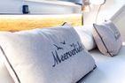  Boddenblick 1 Born auf dem Darß - Nahaufnahme eines Kissens mit Aufschrift ‚Meer verliebt‘ vor Holz-Kopfteil.