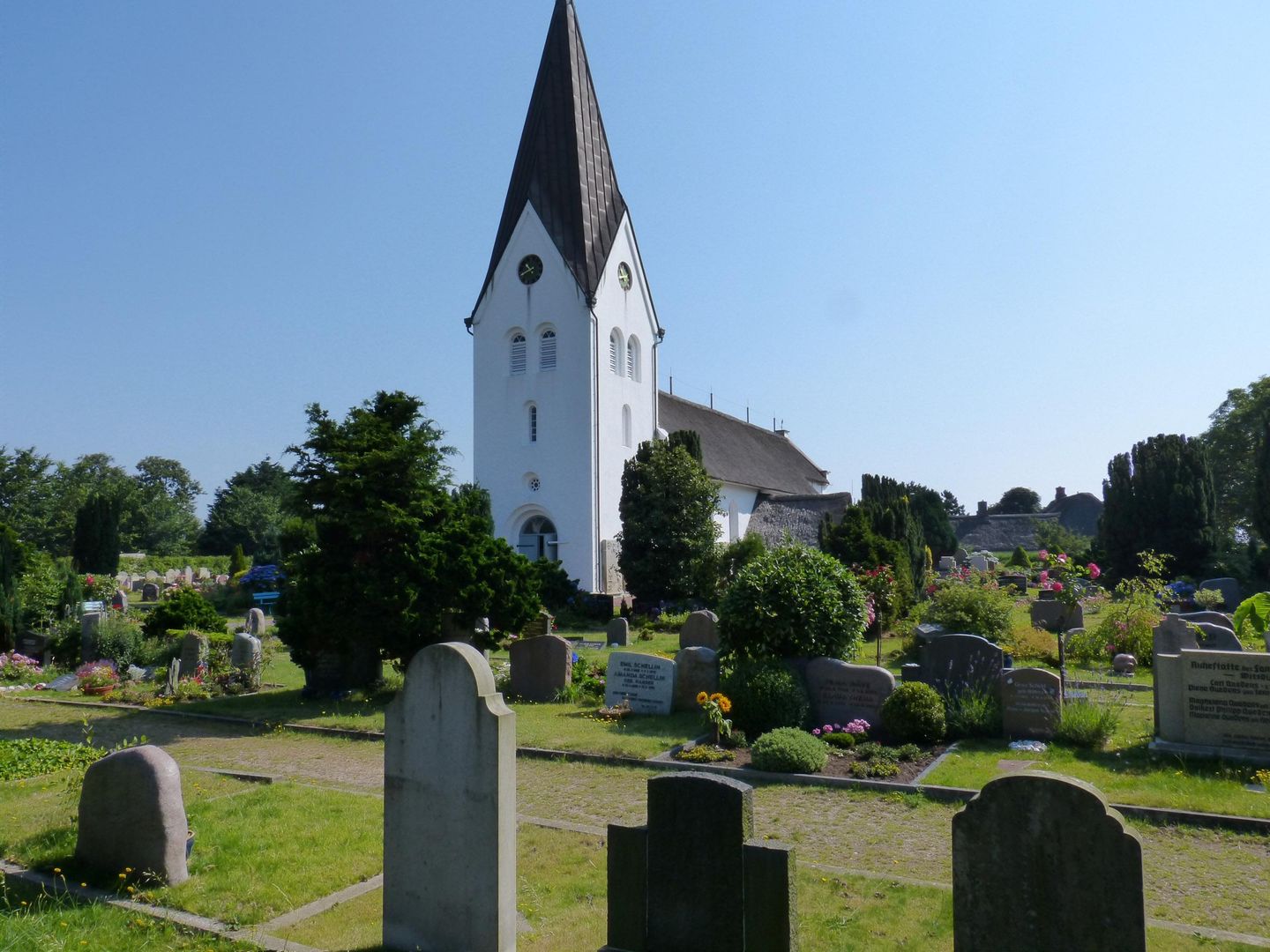 Die St Clemens Kirche in Nebel auf Amrum. Davor die sprechenden Grabsteine von Amrum
