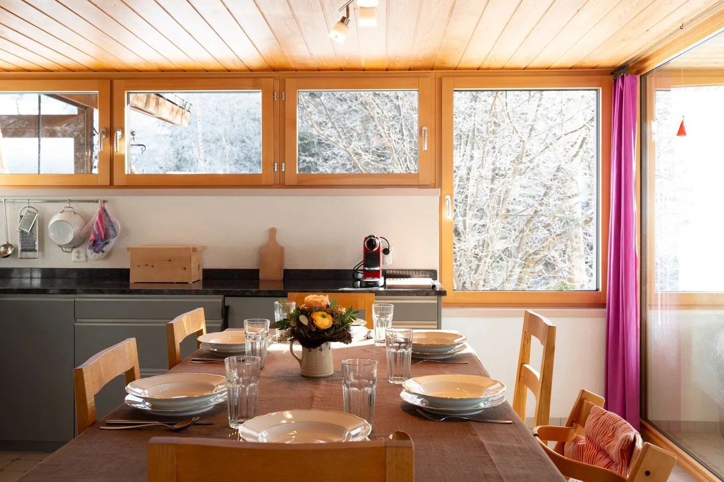 Ferienhaus Casa Chapf Arvenbüel - Dining area with a view of the kitchen and the snow-covered landscape