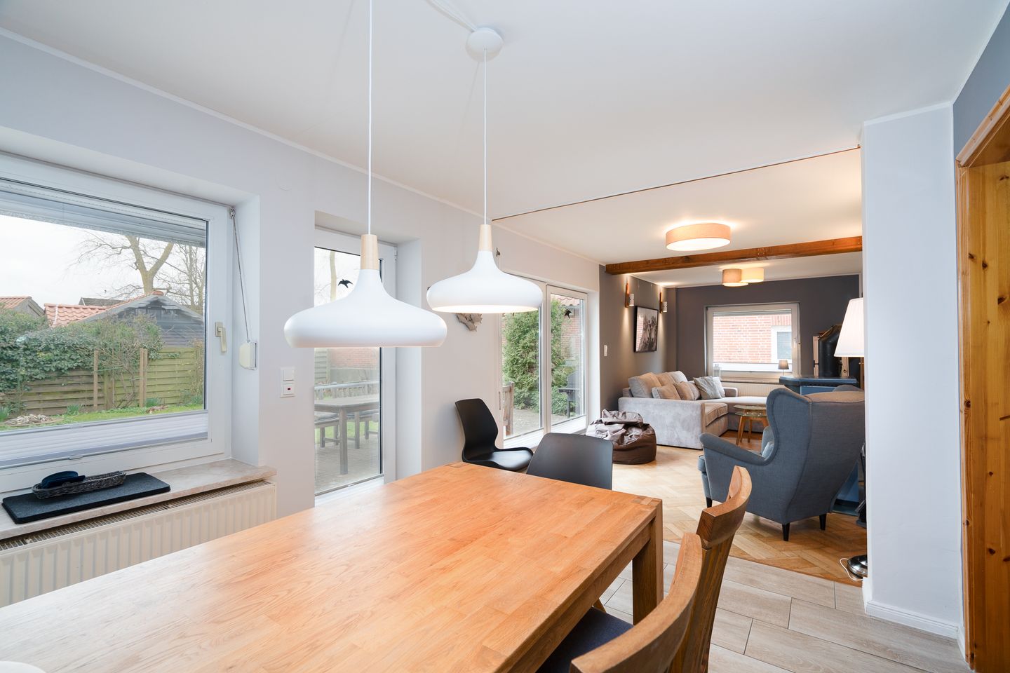 The living kitchen features a wooden table with chairs, large windows, and a cozy couch.