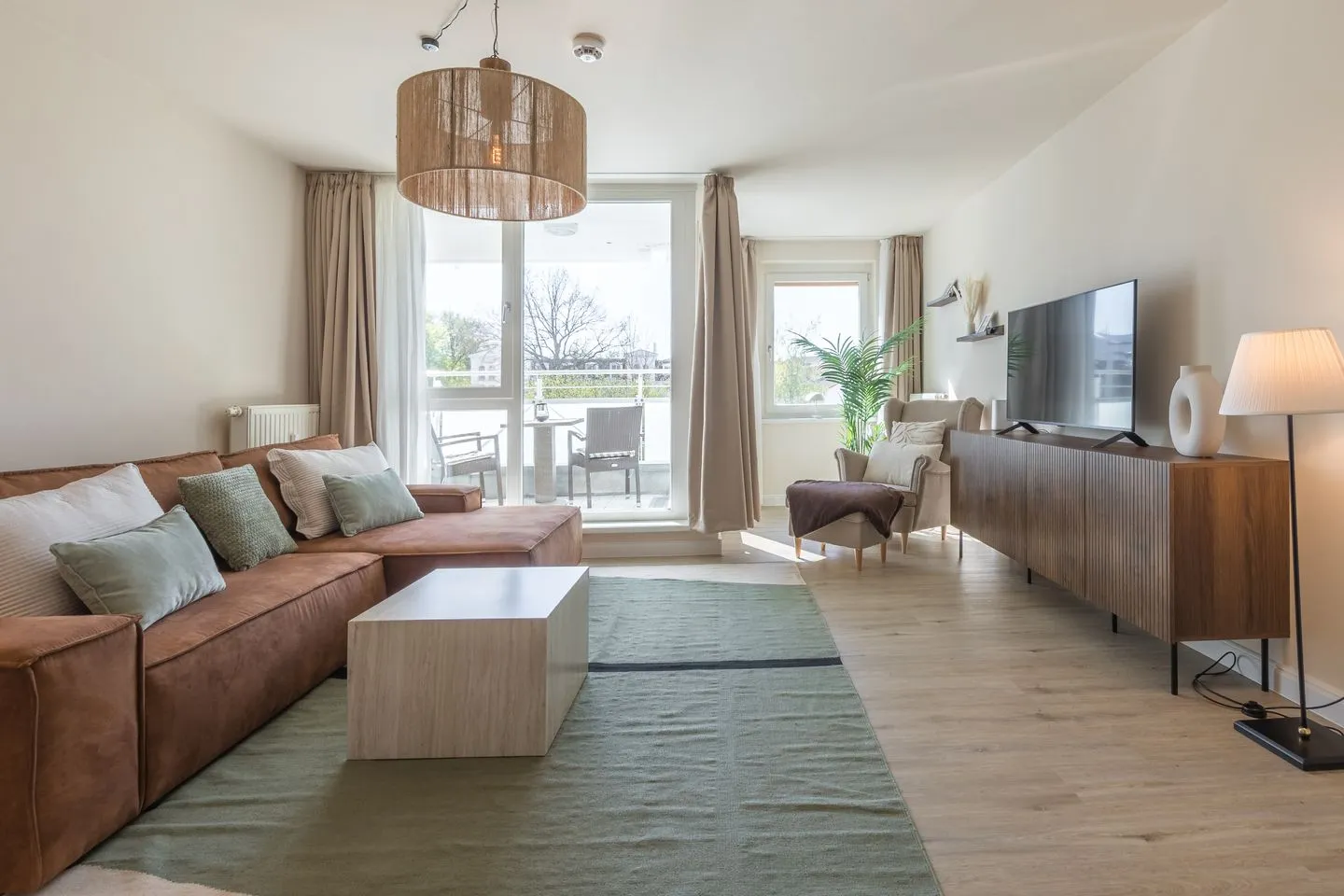 Küstenglück Zingst - Ferienwohnung Küstenglück in Zingst helles Wohnzimmer mit Couch, TV und Zugang zum Balkon
