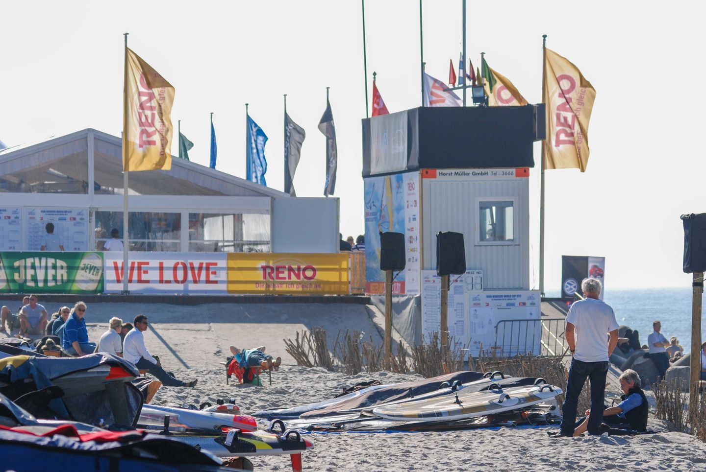 am Strand von Westerland liegen Windsurfbretter und Veranstaltungsfahnen wehen im Wind