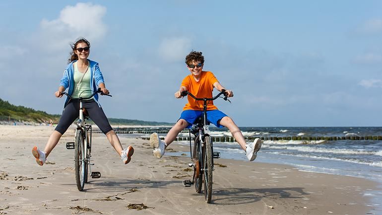 Zwei Kinder fahren Fahrrad am Strand