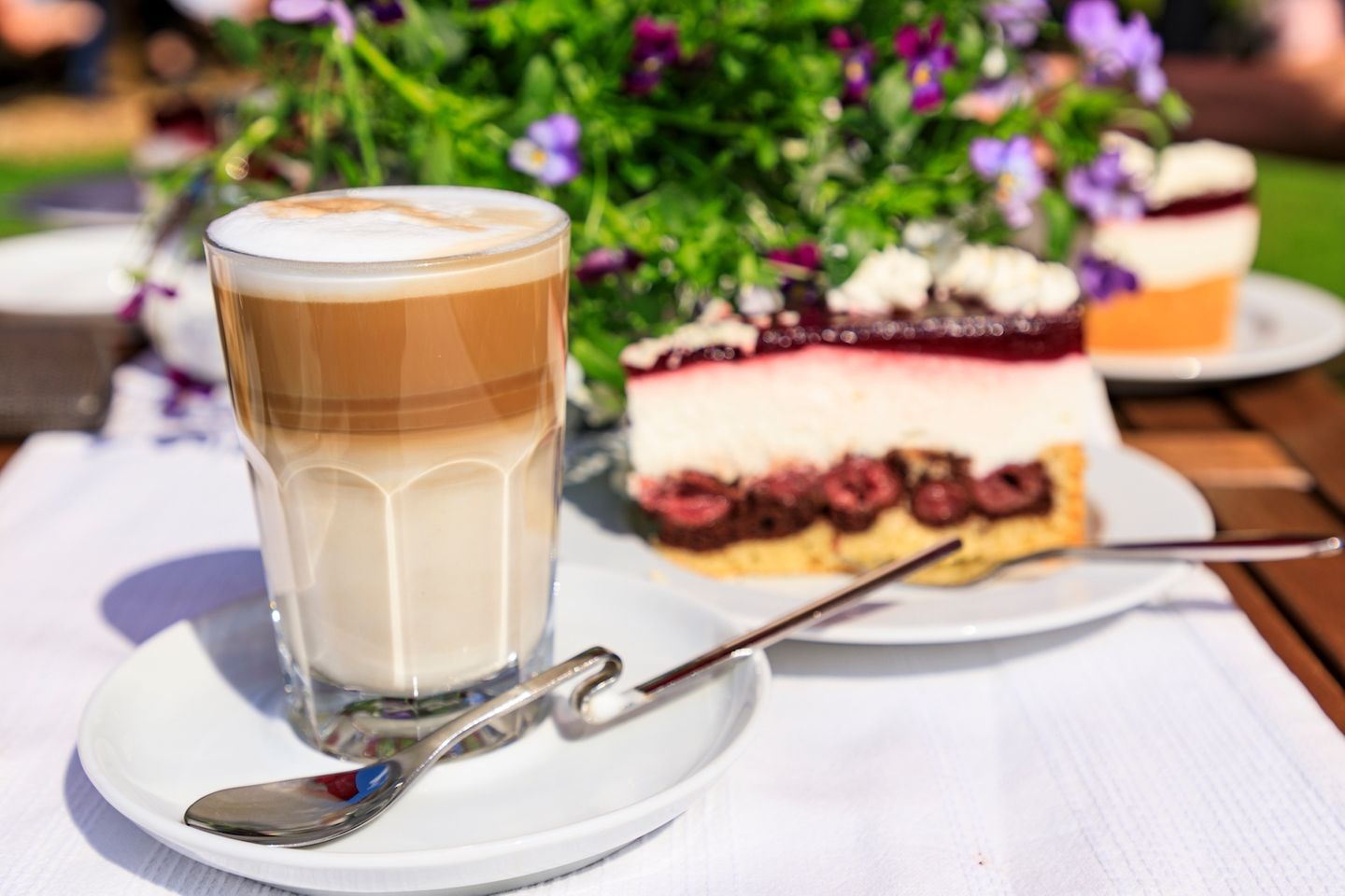 Kaffee und Kuchen auf dem Tisch mit bunten Blumen im Hintergrund
