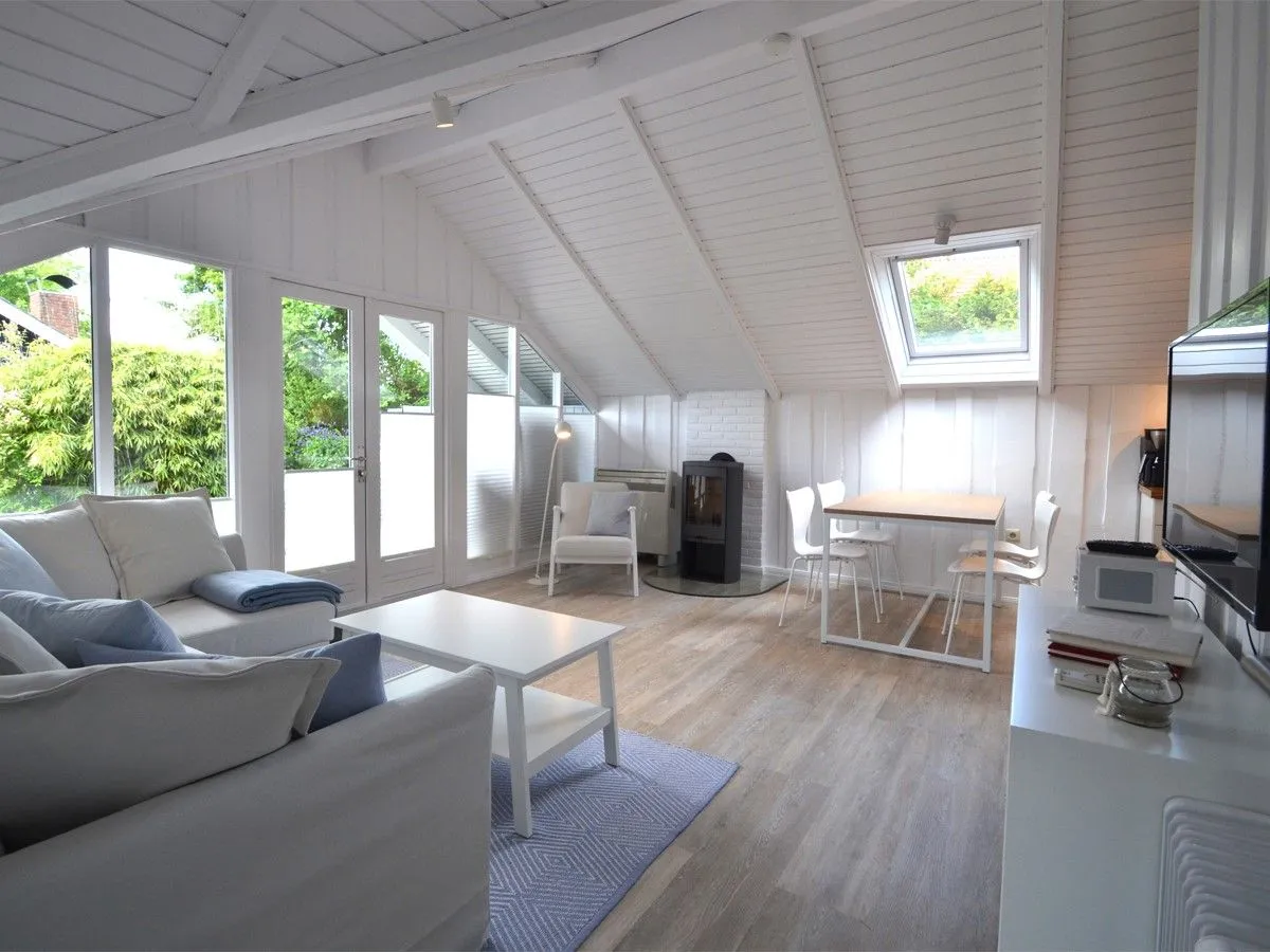Lille Hus Flensburger Förde - Wohnbereich mit Ofen, gemütlichem Sofa und Blick auf die Terrasse