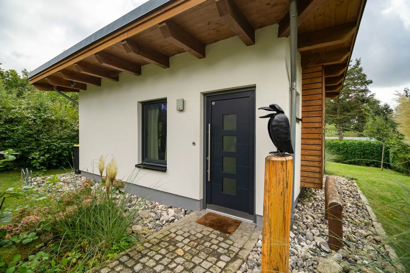 Kleine Sommerliebe Waren (Müritz) - Ferienhaus Kleine Sommerliebe Waren (Müritz) - Moderner Eingangsbereich mit Garten und dekorativem Metallvogel