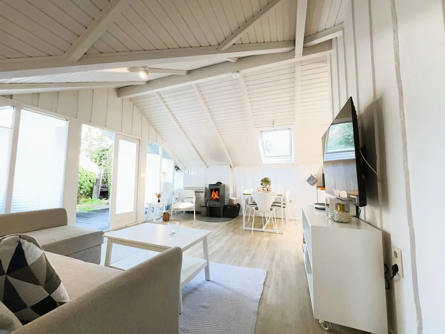 Lille Hus Flensburger Förde - Wohnbereich mit Essplatz, Couchecke, Kamin und TV