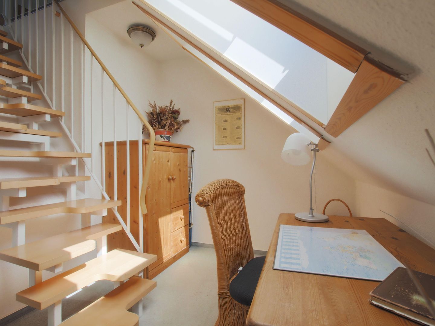 Kleines Zimmer mit Schreibtisch und Raumspartreppe in das Spitzd