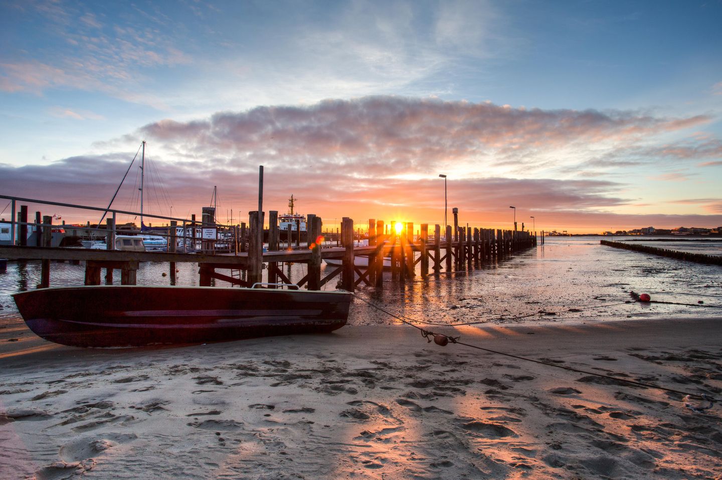 ein kleines Segelboot liegt am Strand von Steenodde auf Amrum, die Sonne geht gerade unter