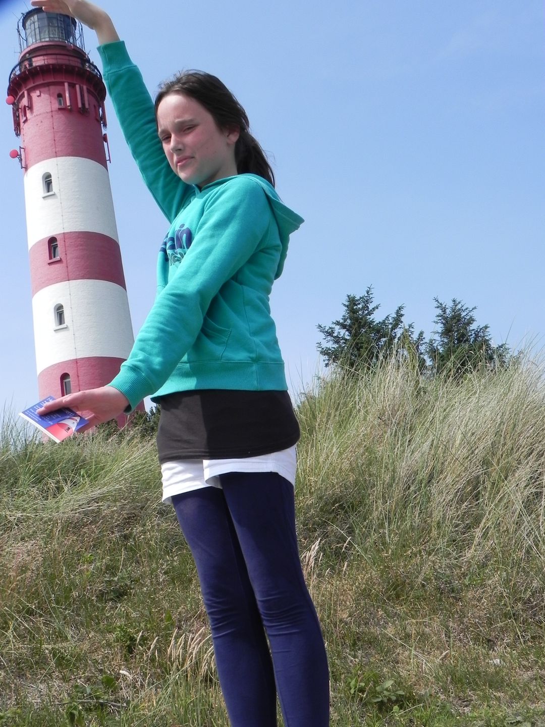 Fotoidee Mädchen hält den Amrumer Leuchtturm zwischen ihren Händen.