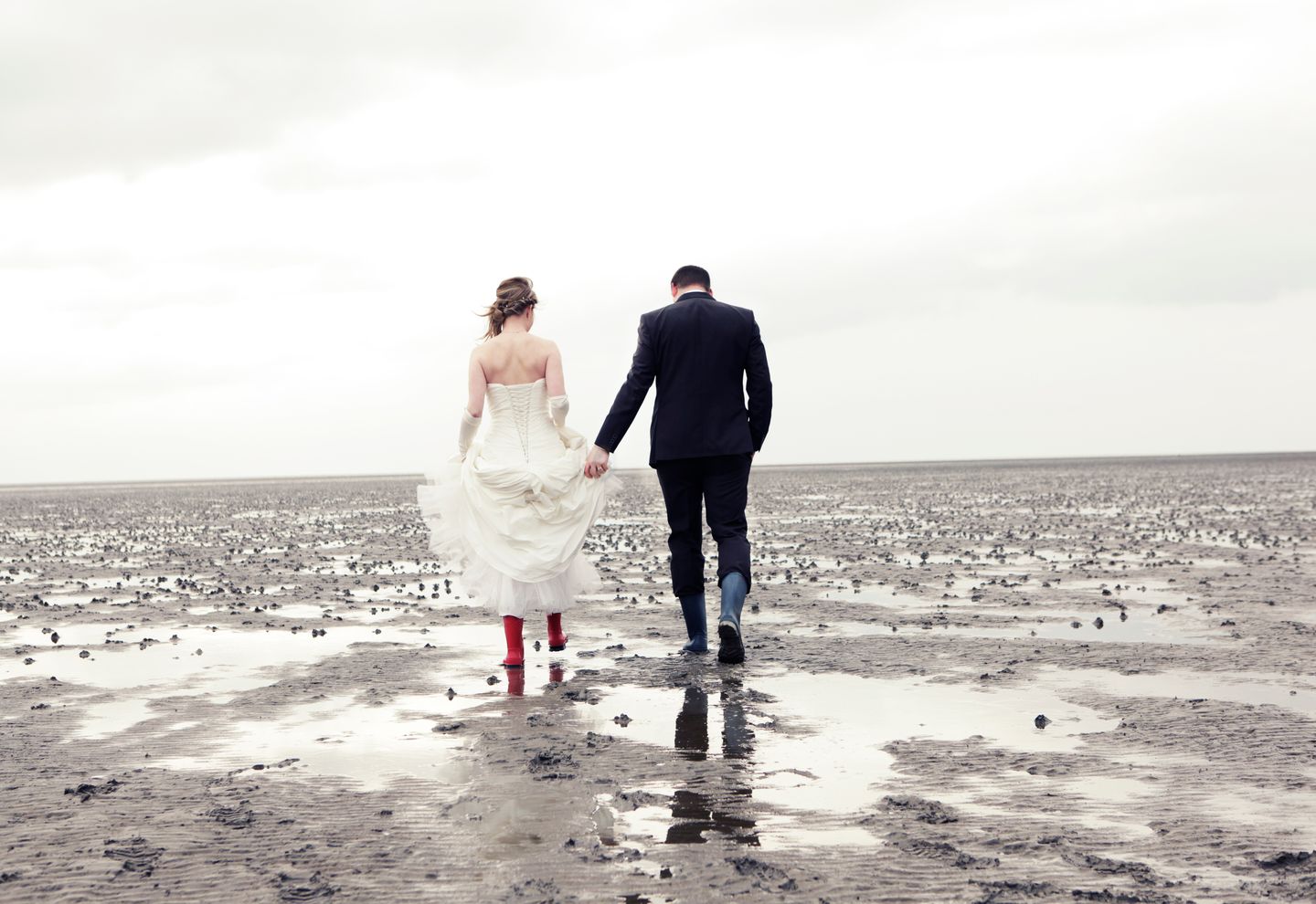 Hochzeitspaar mit Gummistiefeln im Wattenmeer vor der Insel Amrum