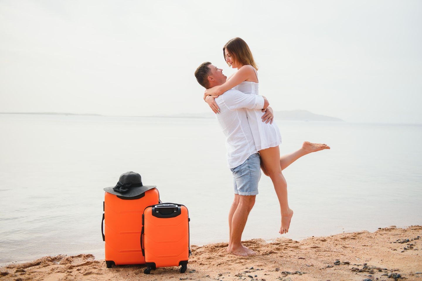 Paar umarmt sich am Strand von der Insel Amrum. Der Mnn hebt die Frau vor Freude in die Luft. Meer im Hintergrund Sand unter den Füssen.