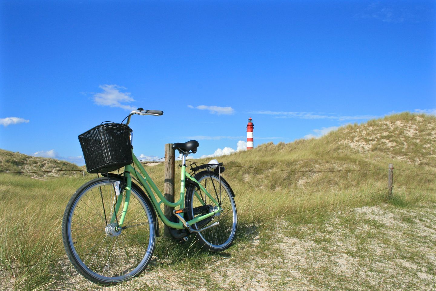 Fahrrad in den Dünen von Amrum. Im Hintergrund ist der Leuctturm zu sehen.