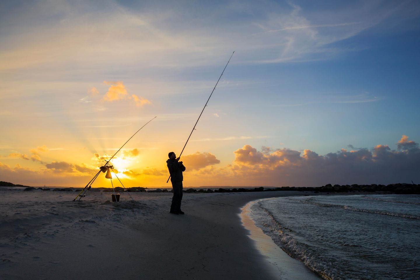 Angler bei Sonnenuntergang am Strand