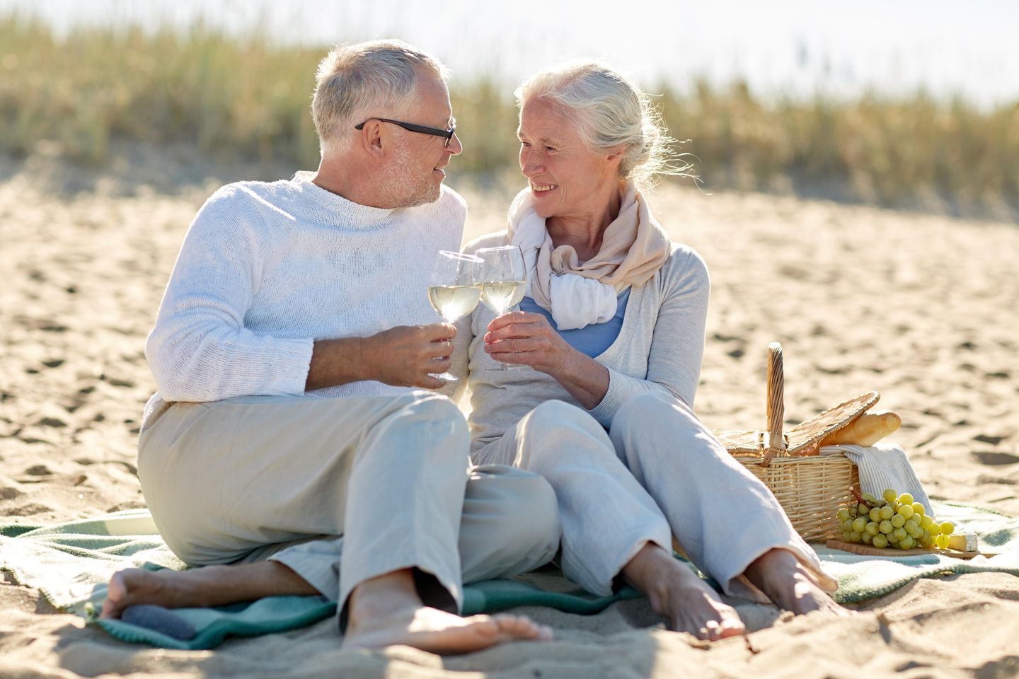 Seniorenpaar mit einer Flasche Wein in den Dünen von Amrum