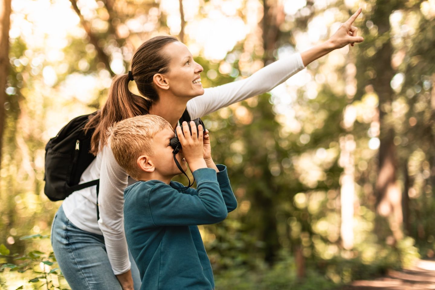 Mutter mit Kinder - Kind hält Fernglas in der Hand und beobachtet Vögel im Wald 