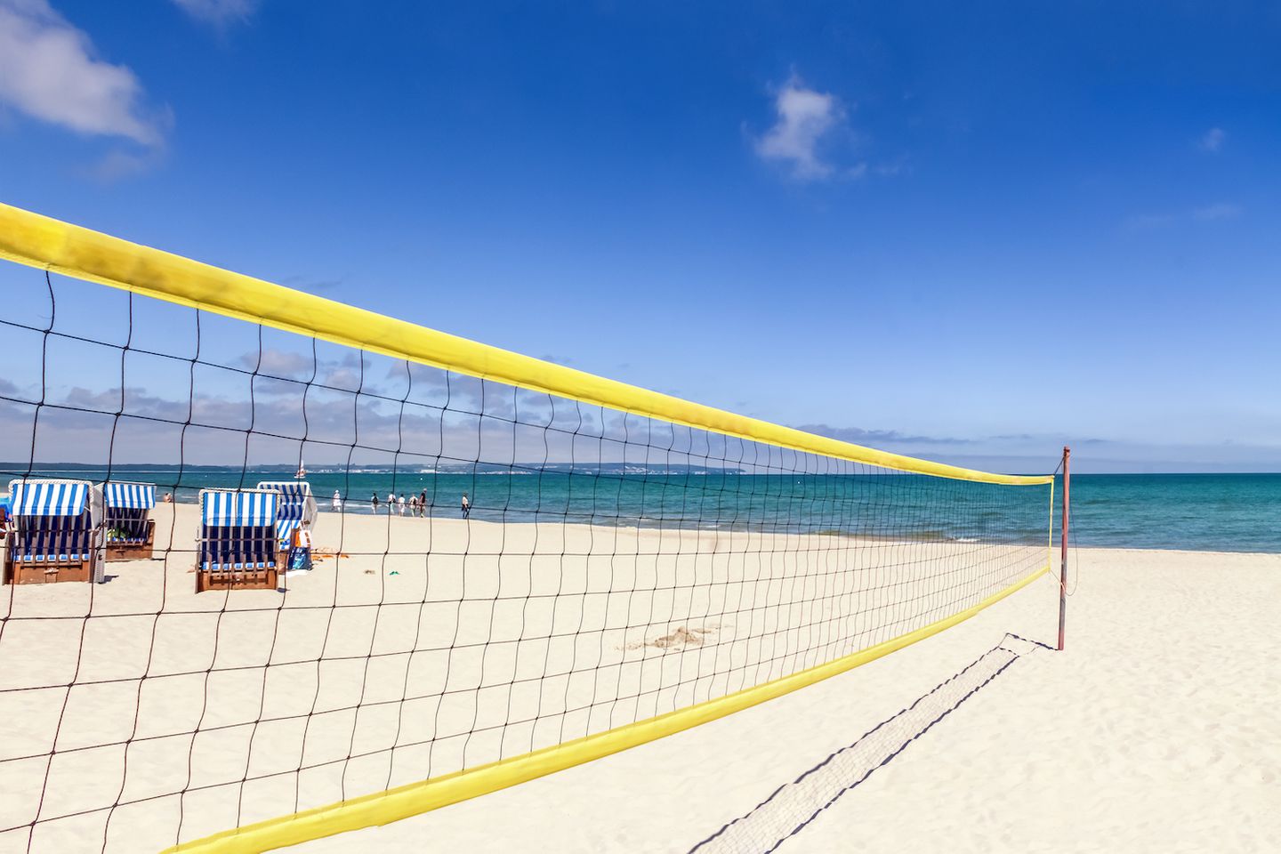 Beachvolleyballnetz am Strand, strahlend blauer Himmel, Strandkörbe im Hintergrund