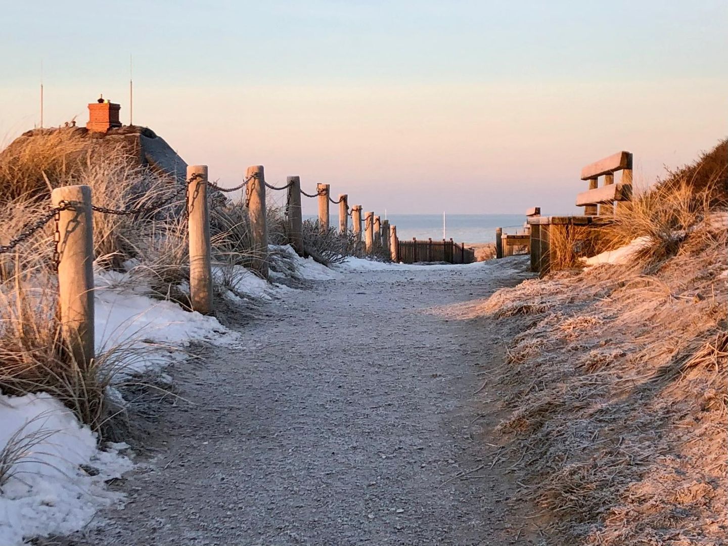 verschneiter Weg und Bank im Abendlicht